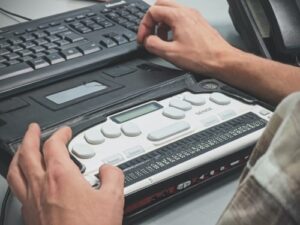 Male hands resting on braille translator display device.